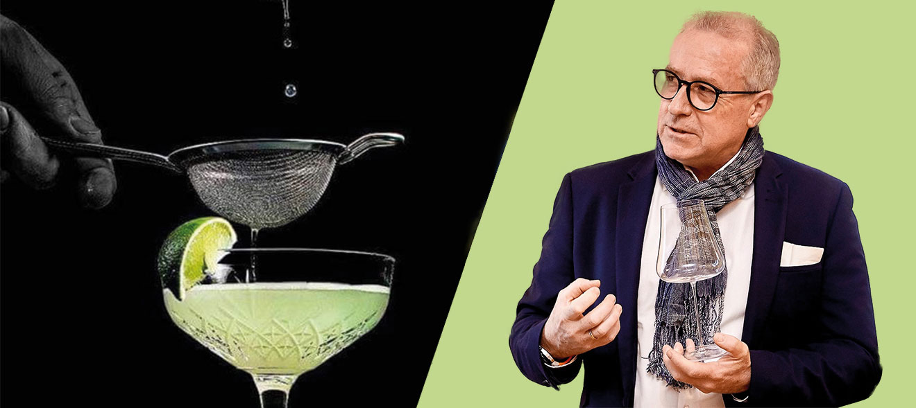 Jesper Efferbach infront of a green backround holding a wine glass. On the left side of the picture you can see a glass of his Timeless Collection infront of a black background.